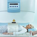 Happy senior woman undergoing for abdomen MRI scan at clinic.